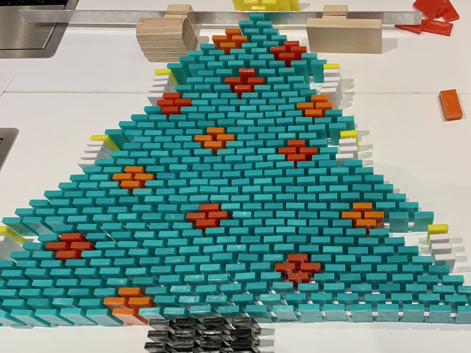 Großer Tannenbaum aus türkisen Dominosteinen mit orangefarbenen Kugeln